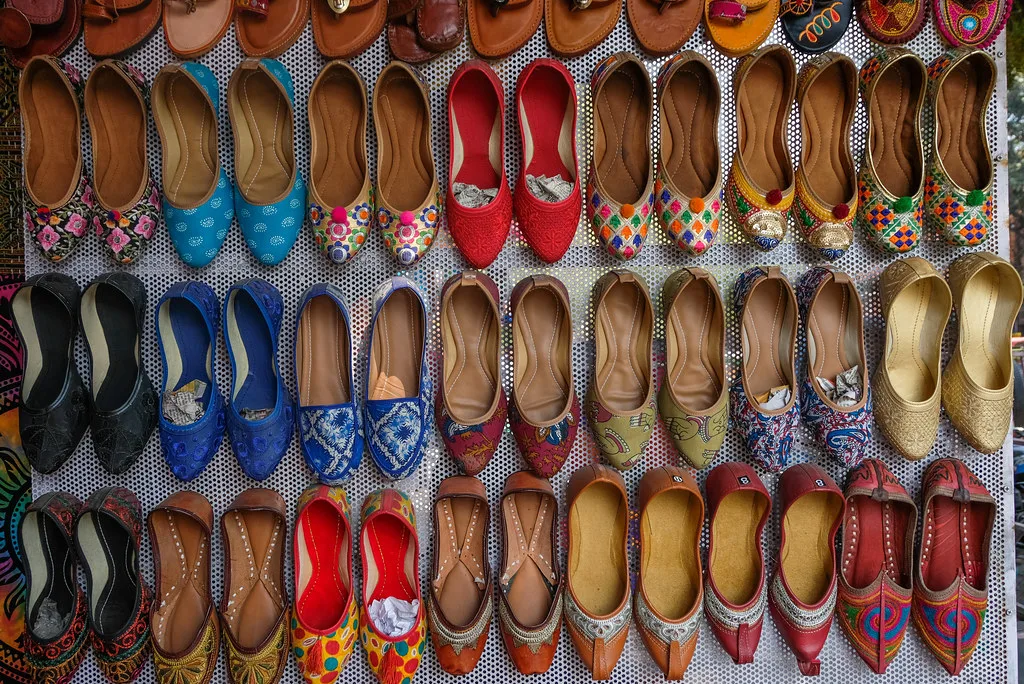 A shop wall covered floor to ceiling in rows of brightly coloured flat shoes.